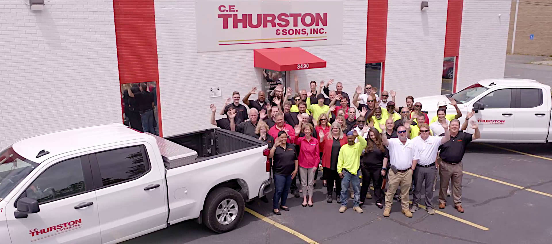 C.E. Thurston team members in front of building waving.
